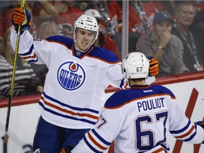 Edmonton Oilers' Connor McDavid, left, celebrates a goal with Benoit Pouliot during NHL action against the Flames in Calgary, Oct. 17, 2015. McDavid finally had a breakout game with two goals and an assist in a 5-2 Oilers victory.