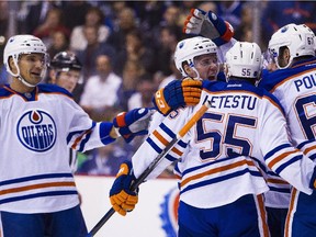 Edmonton Oilers Connor McDavid (97) celebrates with Mark Letestu (55) and Benoit Pouliot (67) after a goal by teammate Nail Yakupov (obscured) against the Vancouver Canucks during the first period of an NHL hockey game in Vancouver, B.C., on Sunday October 18, 2015.