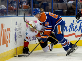 Brandon Davidson lowers the boom on a Calgary Flame and clears the puck during a preseason game in Edmonton last month.