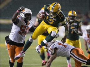 Eskimos quarterback Mike Reilly takes a hit from B.C. Lions players during a CFL game at  Edmonton's Commonwealth Stadium on Oct. 17, 2015.