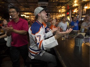 Edmonton Oilers fan Wes Burkard (centre) reacts to a play during the season opening game against the St. Louis Blues at the Pint Downtown on Oct. 8, 2015.