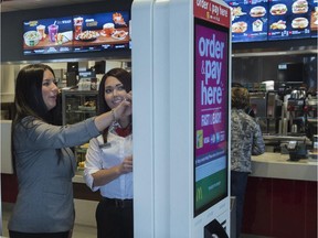 Renee Blacke gets help from employee Erika Anderson on the self-serve touch screen at the Glastonbury McDonald's in west Edmonton. The city is the first market in the country to roll out McDonald's new modernized guest experience including self-order kiosks, create-your-own burger menus and table delivery.