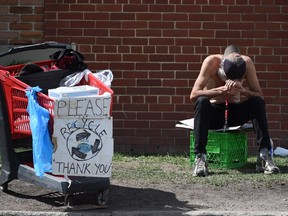 A homeless man sits by his cart.