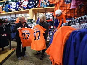 Barbara Watkins and Kim Jalal select orange Oilers jerseys for grandpa Paul Watkins and grandsons Noah and Dathan Jalal, both 12, who are going to Thursday's game, at United Cycle in Edmonton on Tuesday Oct. 14, 2015.