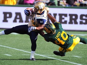 Eskimos' Deon Lacey hauls down Winnipeg's Aaron Woods on a punt return during CFL action in Edmonton in October 2014.