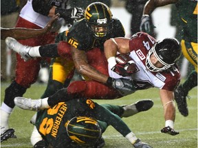 Edmonton Eskimos linebacker Dexter McCoil, top, and Willie Jefferson take down Calgary Stampeders running back Matt Walter during a Canadian Football League game at Commonwealth Stadium on Sept. 12, 2015.