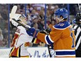 Calgary Flames' Johnny Gaudreau (13), left, is cross-checked by Edmonton Oilers' Nail Yakupov (10) during first period NHL action in Edmonton on Saturday, Oct. 31, 2015.