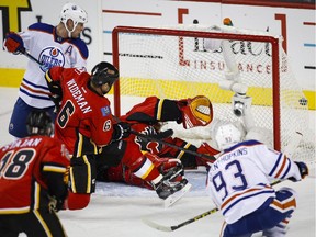 Edmonton Oliers' Ryan Nugent-Hopkins, right, scores on Calgary Flames goalie Jonas Hiller, centre, of Switzerland, as Oilers' Matt Hendricks, left, and Dennis Wideman (6) look on during first period NHL hockey action in Calgary on Saturday, Oct. 17, 2015.