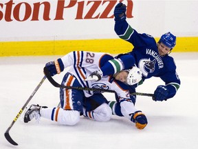 Edmonton Oilers Lauri Korpikoski (28) is checked by Vancouver Canucks Derek Dorsett (15) during the second period of an NHL hockey game in Vancouver, B.C., on Sunday October 18, 2015.