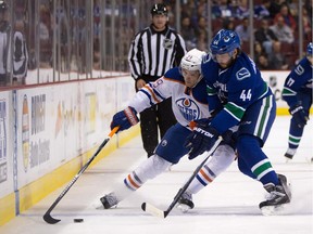 Leon Draisaitl is checked by Vancouver Canucks' Matt Bartkowski during pre-season NHL action in Vancouver, B.C., on Oct. 3, 2015. Draisaitl has been  sent to Edmonton's AHL farm club in Bakersfield, Calif.