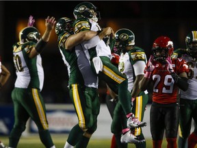 Edmonton Eskimos' Matthew O'Donnell, centre, hoists quarterback Mike Reilly, right, as Calgary Stampeders' Jamar Wall looks on following the Eskimos' win over the Stampeders in Calgary, Saturday, Oct. 10, 2015.