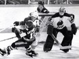 Oilers' Al Hamilton sends Mike Antonovich of the Whalers crashing to the ice while Edmonton goalie Dave Dryden looks on wearing his hybrid mask on April 7, 1979