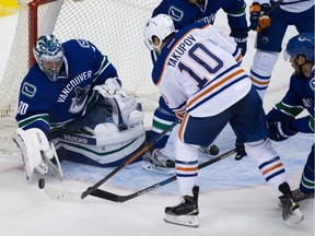 Vancouver Canucks goalie Ryan Miller, left, stops Edmonton Oilers' Nail Yakupov during the second period of a pre-season NHL hockey game in Vancouver on Saturday Oct. 3, 2015.