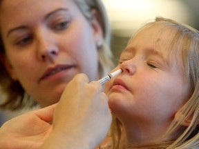 Four-year-old Caitlin Morris steels herself for the nasal vaccination at an Alberta Health Services flu clinic in Calgary on Oct. 20, 2014.