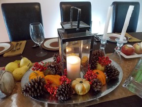 Set a lantern centred on a platter and surround it with gourds, pine cones and glossy red berries.