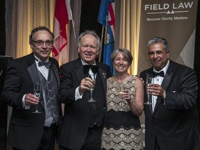Hoisting a glass of champagne to toast the 100th anniversary of Field Law are, left to right, managing partner James Casey; Allan Wachowich, former chief justice of Alberta's Court of Queen's Bench; Doreen Saunderson from Field's Calgary office; and dinner emcee and Field Law partner Sandeep Dhir.