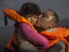 A man kisses his child on a beach after crossing the Aegean Sea in a dinghy with other refugees and migrants from Turkey to the northeastern Greek island of Lesbos, on Tuesday, Nov. 24, 2015.