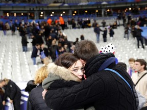 A supporter conforts a friend after invading the pitch of the Stade de France stadium at the end of the international friendly soccer match between France and Germany in Saint Denis, outside Paris, Friday, Nov. 13, 2015. Hundreds of people spilled onto the field of the Stade de France stadium after explosions were heard nearby. French President Francois Hollande says he is closing the country's borders and declaring a state of emergency after several dozen people were killed in a series of unprecedented terrorist attacks.