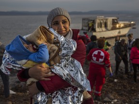 A Syrian woman holds her baby after their arrival on a small boat from the Turkish coast on the northeastern Greek island of Lesbos  Monday, Nov. 16, 2015.