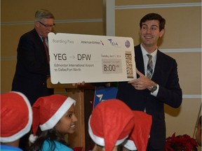 In this December 2013 file photo, Edmonton Mayor Don Iveson holds up a large boarding pass after Edmonton International Airport (EIA) announced new flights from Edmonton to Dallas/Fort Worth, Texas with American Airlines. American Airlines intends to stop offering the flights because of the Canadian dollar's low value.