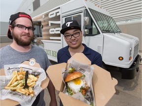 Truck 1879 chef Parker Regimbald, left, and food truck manager Tony Mah pose with a Korean pulled pork burger with fried egg and duck fat kennebec garlic fries drizzled with Bearnaise sauce at Northlands in Edmonton on July 8, 2015.