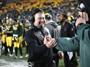 Edmonton Eskimos head coach Chris Jones congratulates another member of the coaching staff after getting doused with ice water and beating the Montreal Alouettes on Nov. 1, 2015, at Commonwealth Stadium in the Canadian Football League team's final game of the regular season to finish in first place in the West Division.