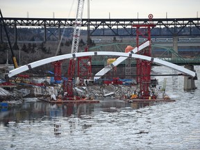 The new Walterdale Bridge arch has moved closer to the river with most of it hanging over the water .