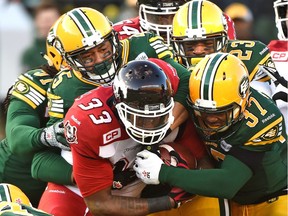 Edmonton Eskimos' Otha Foster (37), Marcell Young (23) and Dexter McCoil (45) stack up Calgary Stampeders' Jerome Messam (33) during the CFL West Division final at Commonwealth Stadium in Edmonton on Sunday.