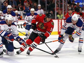 Andrew Desjardins of the Chicago Blackhawks controls the puck between Andrej Sekera, left, and Leon Draisaitl of the Edmonton Oilers during NHL action in Chicago on Sunday, Nov. 8, 2015. The Blackhawks defeated the Oilers 4-2.