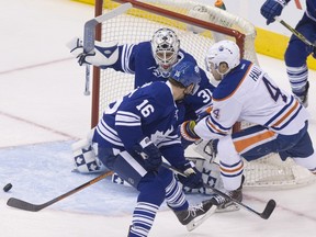 Toronto Maple Leafs goaltender Garret Sparks eyes the puck as Edmonton Oilers' Taylor Hall, right, and Maple Leafs' Nick Spaling battle for possession in front of the goal during first-period NHL action in Toronto on Monday, Nov. 30, 2015.