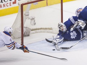 Toronto Maple Leafs goaltender Garret Sparks, centre, and Edmonton Oilers' Taylor Hall, left, stretch to reach a puck after Sparks made a save on Oilers' Teddy Purcell, right, during second-period NHL action in Toronto on Monday, Nov. 30, 2015.