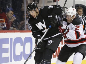 New York Islanders defenseman Travis Hamonic (3) tries to keep New Jersey Devils defenseman John Moore (2) away from the puck during the second period of an NHL hockey game in New York, Tuesday, Nov. 3, 2015. (AP Photo/Kathy Willens)