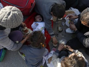 Migrants eat as they wait to register with the police at a refugee centre in the southern Serbian town of Presevo on Monday, Nov. 16, 2015.