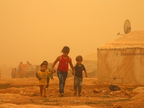 Syrian children walk during a sandstorm on Sept. 7, 2015, at a refugee camp on the outskirts of the eastern Lebanese city of Baalbek.  The lead settlement agency for government-sponsored refugees in Edmonton could help three times as many refugees in the next six weeks as it normally helps in an entire year.