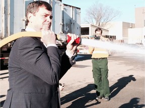 Alberta Forestry Minister Oneil Carlier uses a fire hose during an event Friday, Nov. 6 to thank fire crews for a challenging 2015 season battling forest fires.