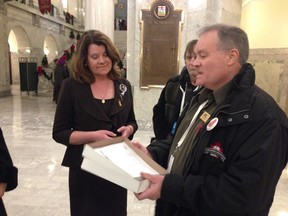Mike Dempsey, vice-president of the Alberta Union of Provincial Employees, presents a petition Wednesday to Advanced Education Minister Lori Sigurdson, calling for a commitment to keep Athabasca University in Athabasca.