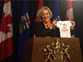 Premier Rachel Notley holds up a onesie emblazoned with a quote from former federal NDP leader Jack Layton on Wednesday, Nov. 4, 2015. The onesie is destined for Calgary-Varsity NDP MLA Stephanie McLean, who will deliver her first child in February - becoming the first sitting MLA in Alberta's history to deliver a baby during her term in office.