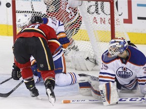 Edmonton Oilers goalie Anders Nilsson, right, looks on as Calgary Flames' Matt Stajan bounces a puck into the net during the second period of an NHL game at Calgary on Sunday, Dec. 27, 2015.