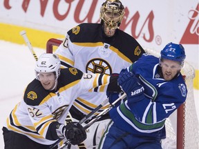Boston Bruins defenceman Zach Trotman tries to clear Vancouver Canucks forward Daniel Sedin from in front of Bruins goalie Tuukka Rask  during NHL action in Vancouver on Dec. 5, 2015.