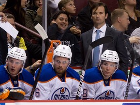 Edmonton Oilers head coach Dallas Eakins, top, stands on the bench as players Martin Marincin, of Slovakia, from left, Jesse Joensuu, of Finland, Tyler Pitlick and Mark Arcobello look on during the first period of a pre-season NHL hockey game against the Vancouver Canucks in Vancouver, B.C., on Wednesday September 18, 2013.