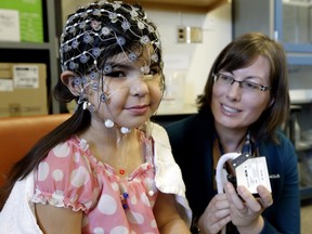 Sandra Wiebe of the University of Alberta watches as Kaia Anderson-Fillier, 4, is fitted with a sensor cap to record her brain activity and measure impulse control while she plays a computer video game.