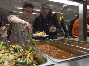 Cecilia Hoang serves up a plate for  J.D. Bull during the free lunch at Hoang Long Fresh Market downtown on Wednesday, Dec. 30, 2015.