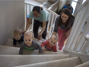 Nanny Jennifer Domingo, left, and mother Leslie Low help guide the Low triplets, from left, Thomas, Luke, and Mason, up the stairs as they hed to bed for a nap in February 2015.