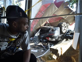 Apartment resident Shurlon Trotman looks on as police investigate the scene of a fatal single-vehicle rollover in Edmonton July 8, 2015.