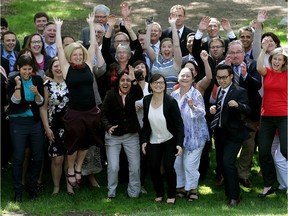Alberta Premier Rachel Notley (leaping off the ground, left) and members of her caucus have some fun while posing for a group photo outside the legislature on June 25, 2015.