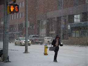 A pedestrian walks through the falling snow downtown in Edmonton, Dec. 18, 2015.