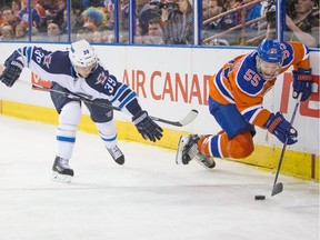 Edmonton Oilers' Mark Letestu (55) dives for the puck against Winnipeg Jets' Toby Enstrom (39) during NHL action at Rexall Place in Edmonton on December 21, 2015.