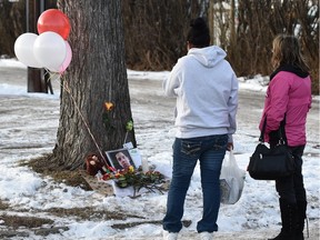 People stop by a memorial set up after a man died following an altercation behind Duster's Pub at 118th Ave. and 64th St. early on Dec. 3 in Edmonton.