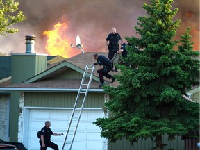 Edmonton police officers climb on the roof of a house in Callingwood after a gun battle on Monday, June 8, 2015. Const. Daniel Woodall was killed and Sgt. Jason Harley was wounded in the shooting. Fire crews were also called to a burning house at the scene.