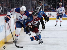 Lauri Korpikoski of the Edmonton Oilers and Tyson Barrie of the Colorado Avalanche pursue the puck at Pepsi Center on Dec. 19, 2015 in Denver, Colo.